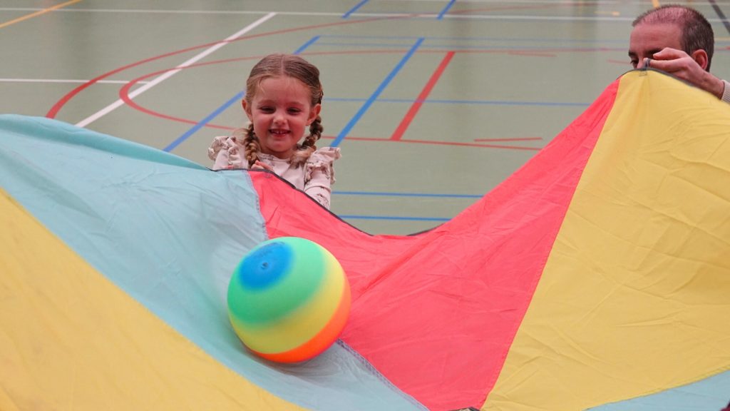 Meisje houdt een parachute vast met daarin een gekleurde bal. (foto: Team Sportservice)