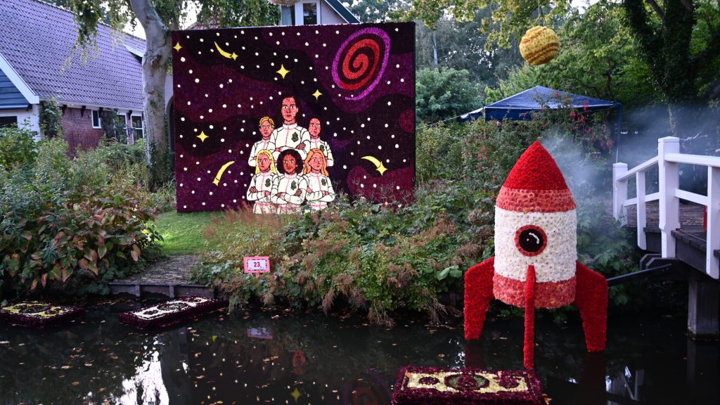 Mozaïek van dahlia's: 6 astronauten en een ruimteschip. Deze stonden in een tuin aan de Dorpsstraat in Nieuwe Niedorp tijdens de Floralia 2026.