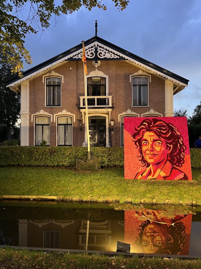 Dahlia mozaïek van Diewertje Blok voor een mooi statig huis vanaf het water gezien