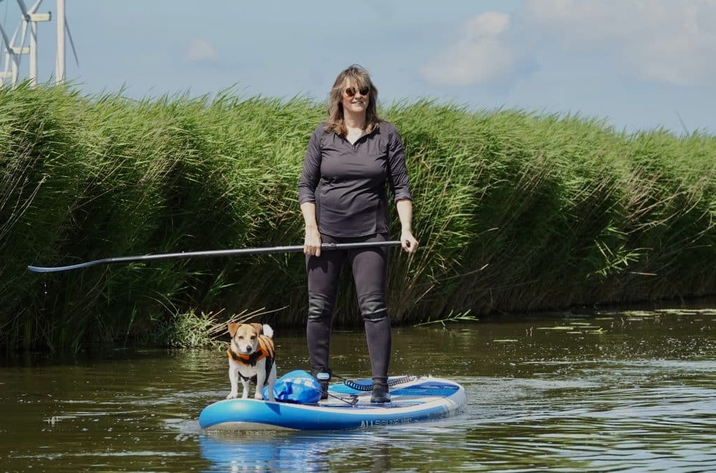 Peddelen in Hollands Kroon. Vrouw op een sup met hond voorop op het water