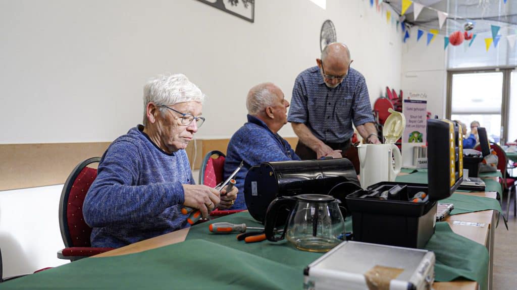 Vrijwilligers van het repair café aan de slag met spullen van inwoners